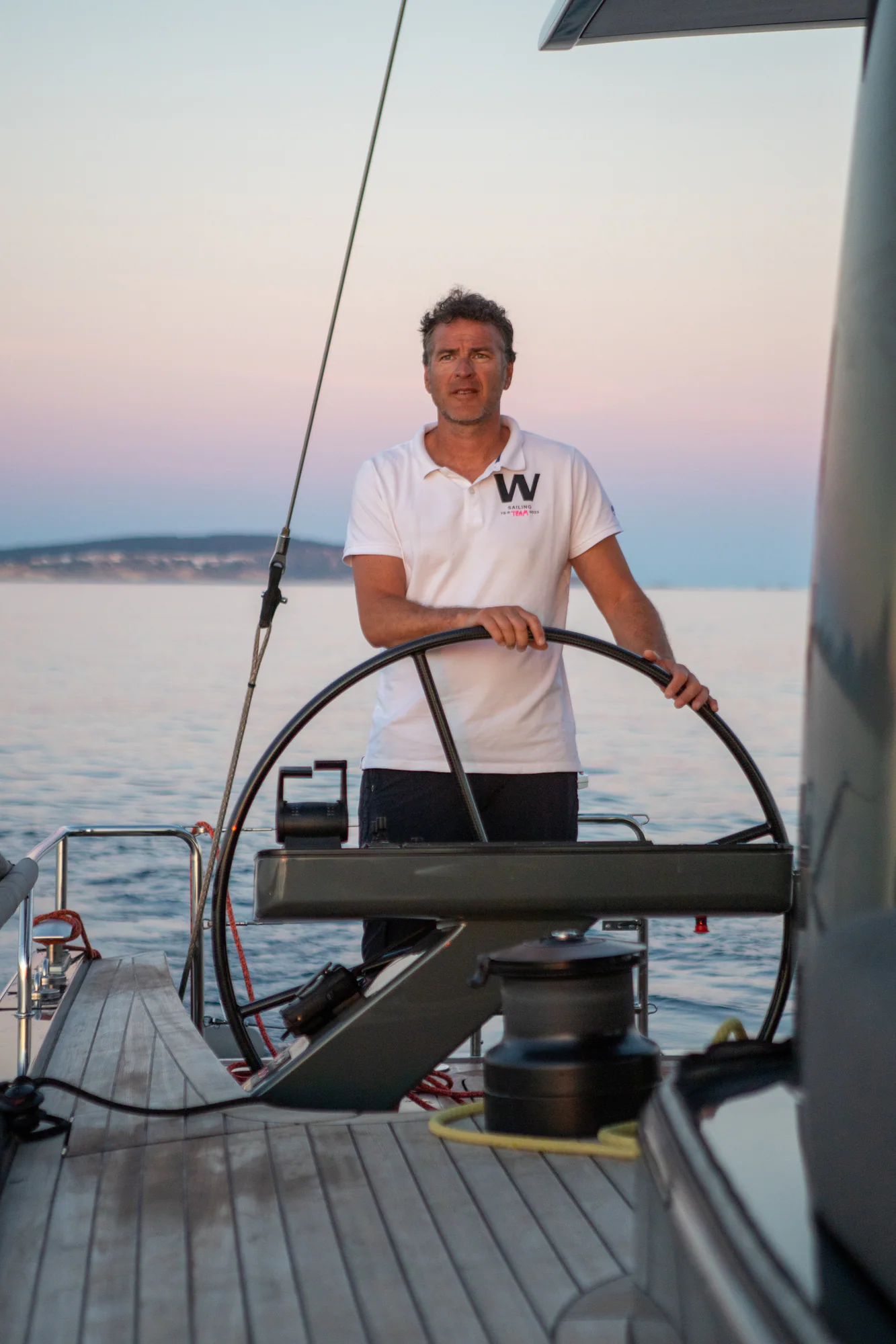 The captain at the helm of Sailing Yacht W at golden hour